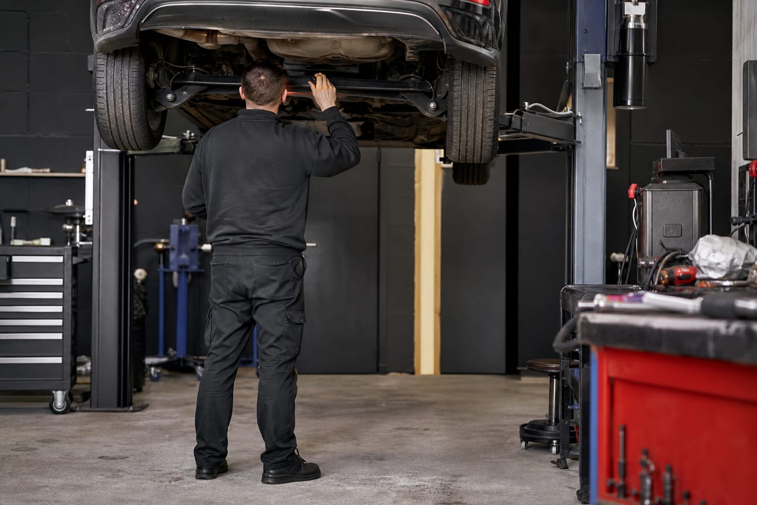A mechanic inspecting a car on a vehicle lift inside a UK garage